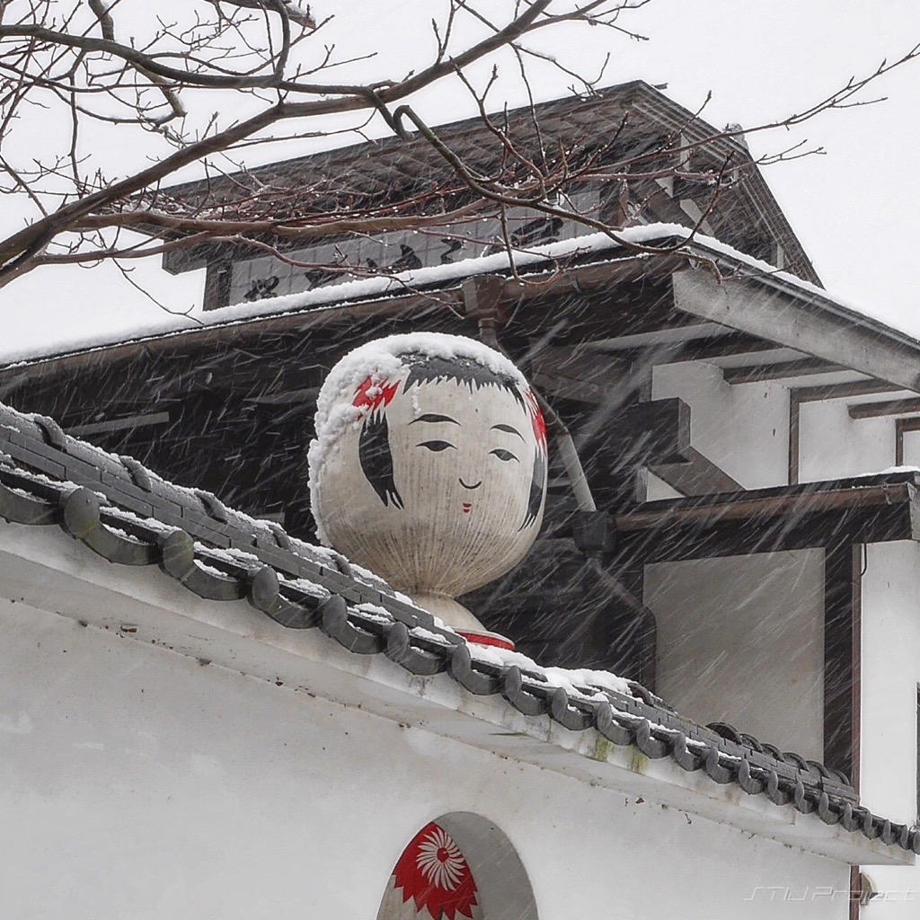 塀の上から”いらっしゃいませ” 〜店先の巨大こけしオブジェ